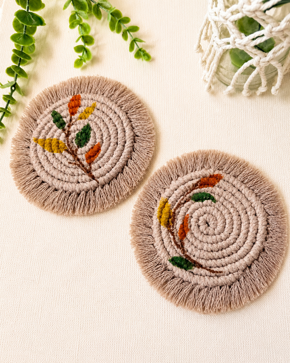 Set of 2 handmade boho floral macrame coasters with cotton cord, embroidered leaf and flower designs, beige fringe and earthy colours.