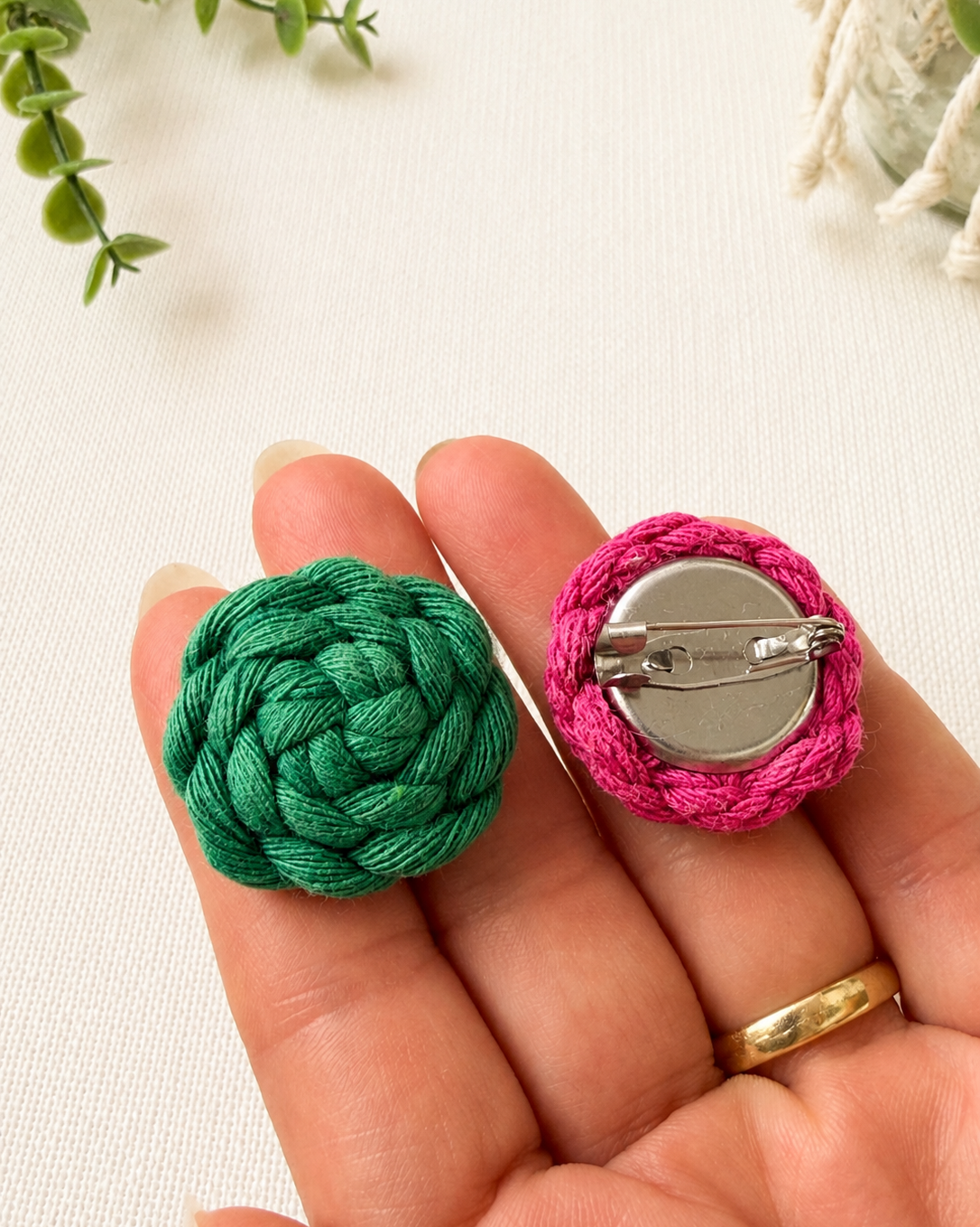 Handmade macrame button brooch shown in hand for size reference