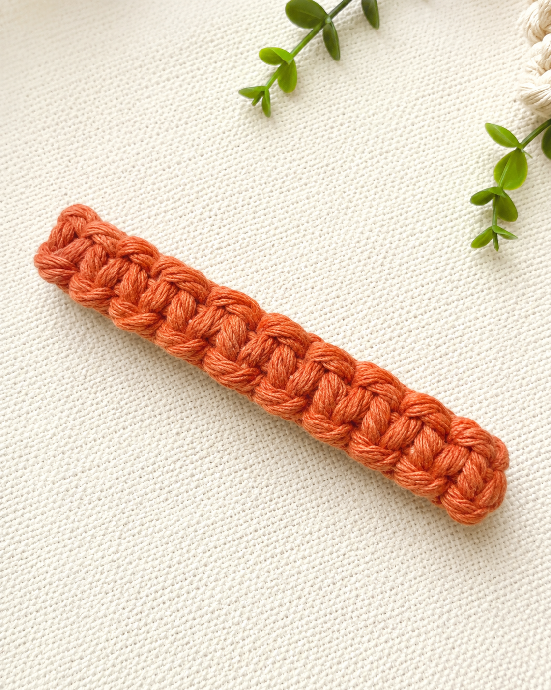 Close-up detail of terracotta macramé hair clip showing knot texture and craftsmanship