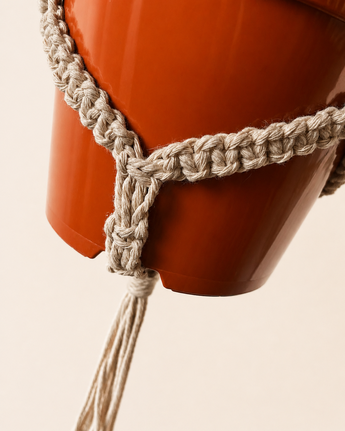 Close up of cotton macrame plant holder supporting a hanging plant pot