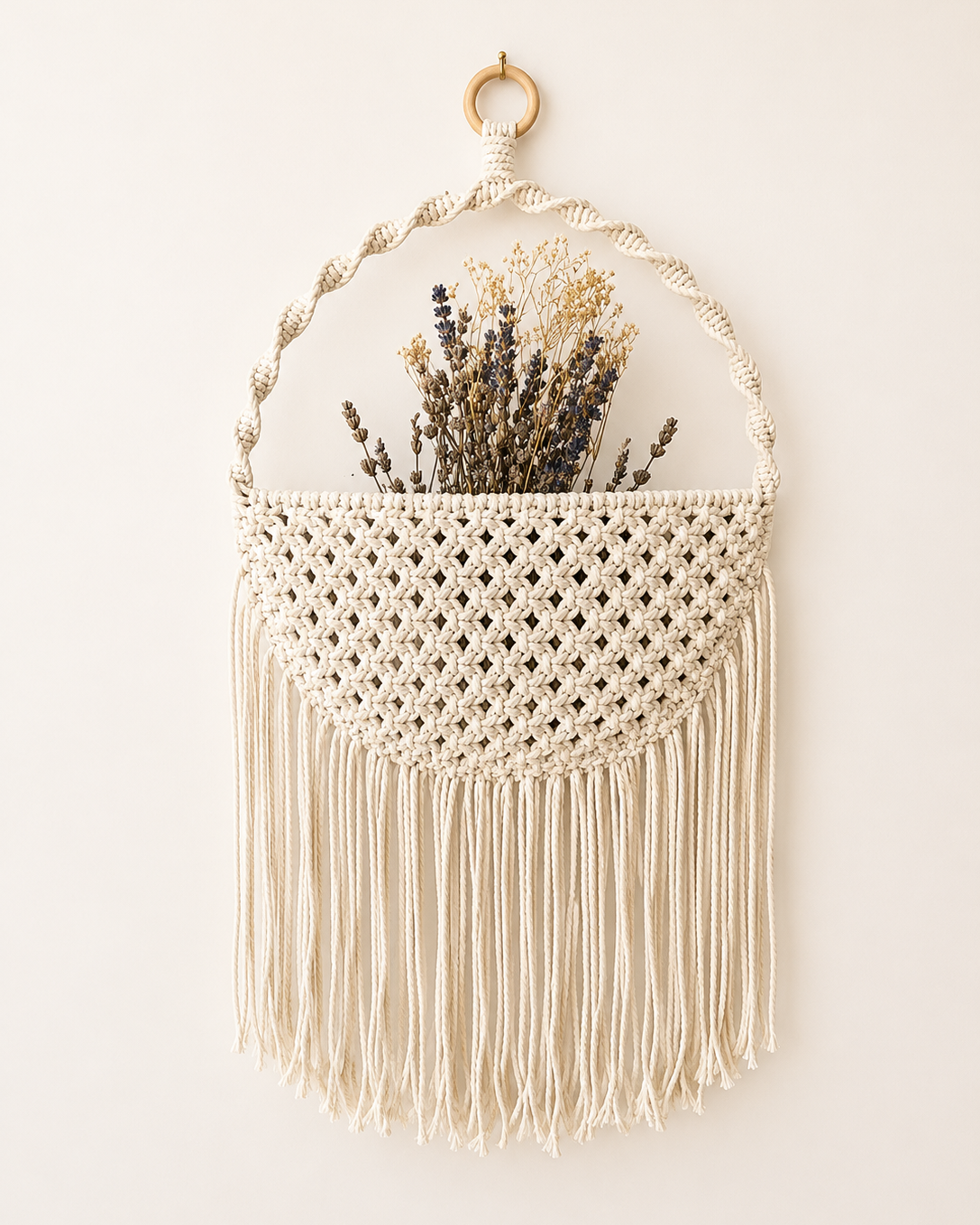 Back view of a handmade double-sided macrame wall pocket with soft cotton fringe.