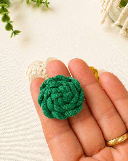Handmade emerald green macrame button brooch shown in hand for size reference
