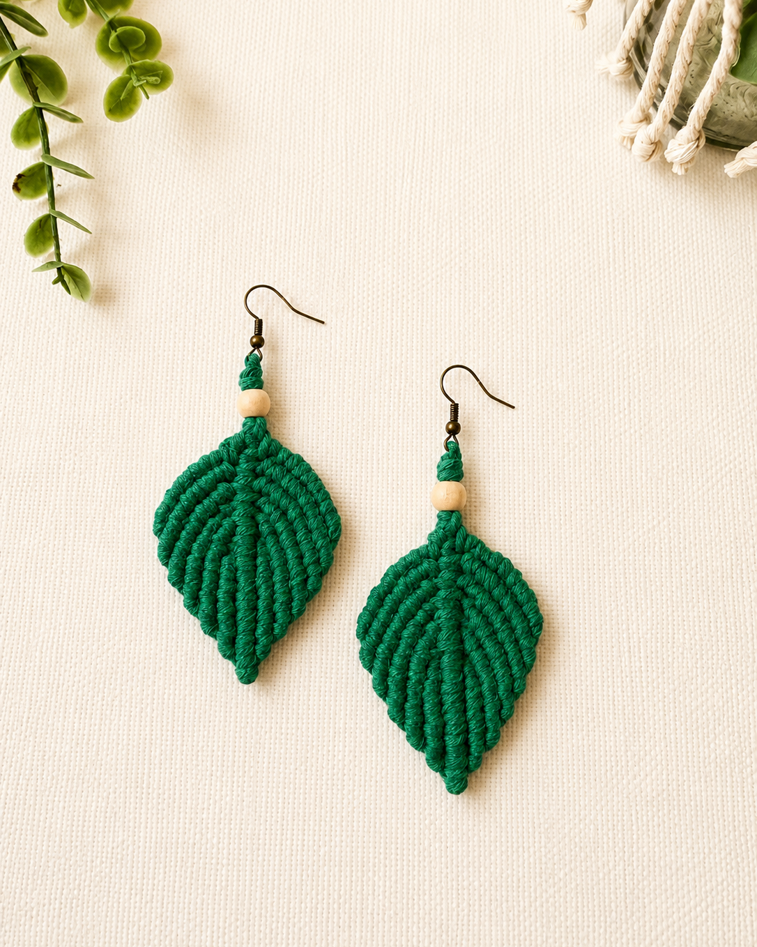 Handmade emerald green macrame leaf earrings with wooden bead detail and antique bronze hooks.