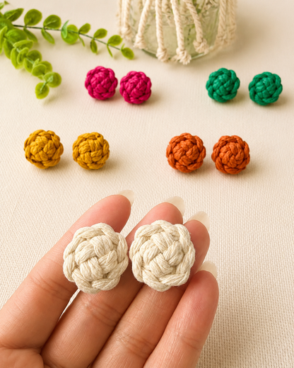 Off-white macramé flower stud earrings shown in hand to demonstrate size and detail.