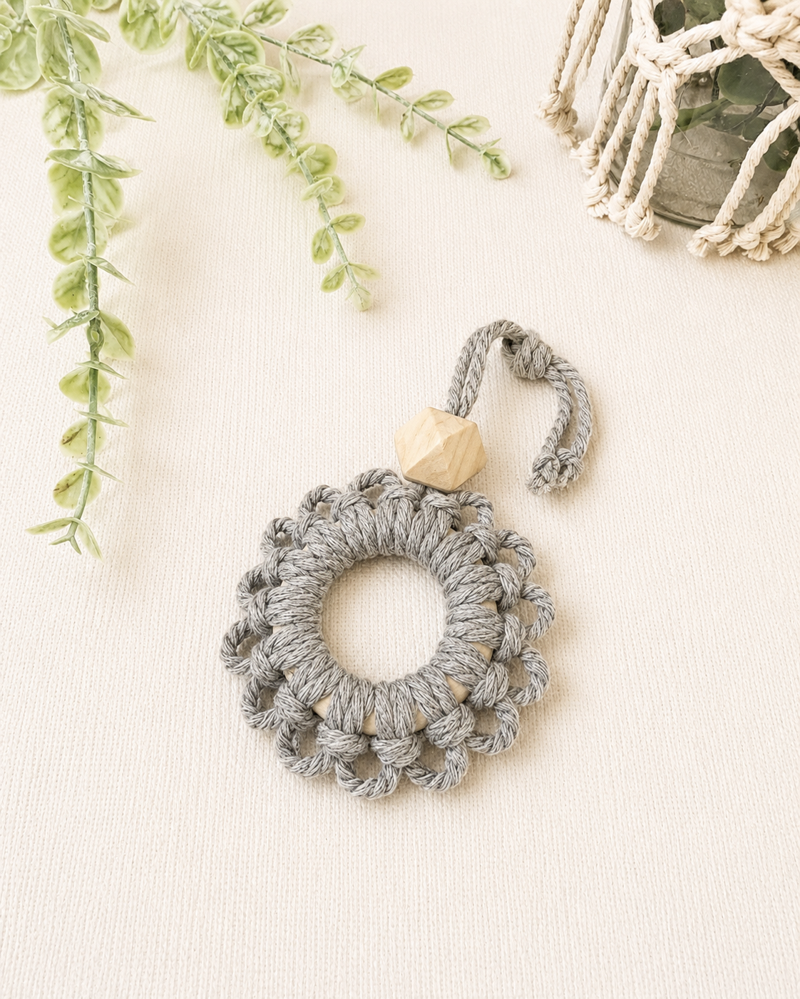 Handmade grey macrame flower car diffuser with a natural wooden bead for essential oils and modern car décor.