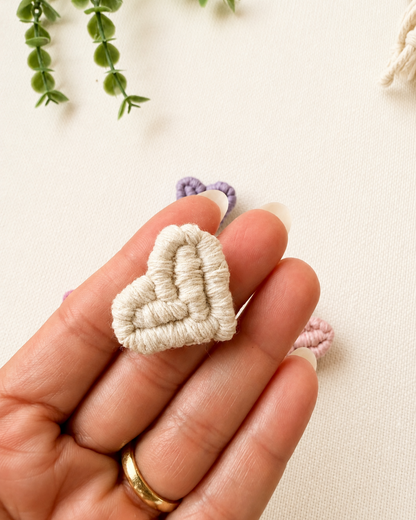 Handmade off white macrame heart brooch shown in hand for size reference