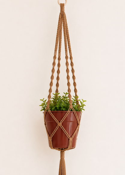 Light brown macrame plant hanger handmade with cotton cord and wooden ring, featuring spiral and square knot details with a terracotta pot on an off-white background.