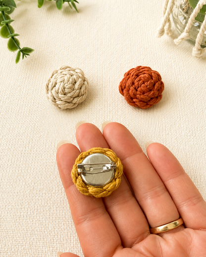 Back of handmade macrame button brooch showing secure metal pin fastening