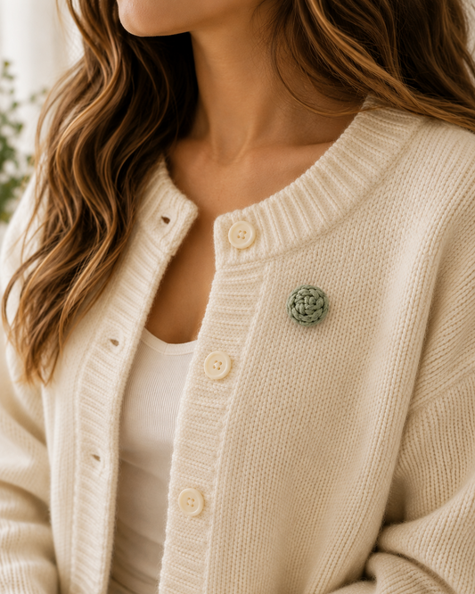Handmade macrame button brooch pinned to a cream knitted cardigan for a cosy boho style.