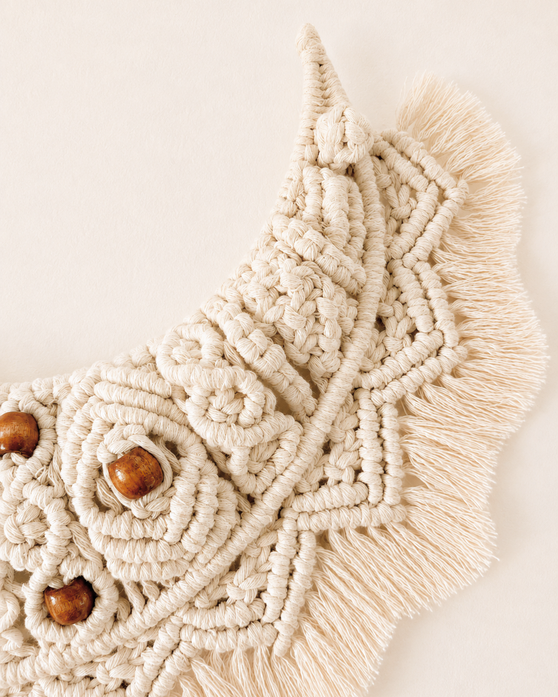 Close-up of off-white macrame crescent moon wall hanging with handmade knotwork and fringe