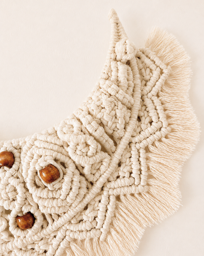Close-up of off-white macrame crescent moon wall hanging with handmade knotwork and fringe