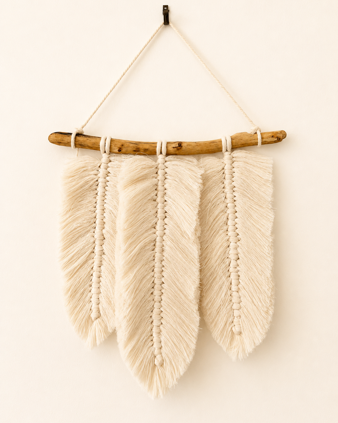 Handmade macrame feather wall hanging with three Egyptian cotton feathers on a natural wood branch