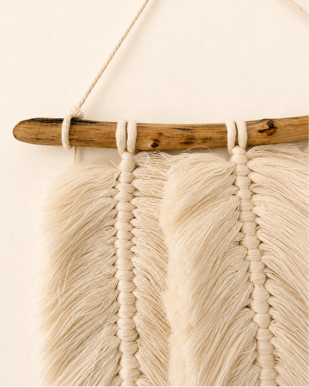 Close-up of handmade macrame feathers hanging from a natural wood branch