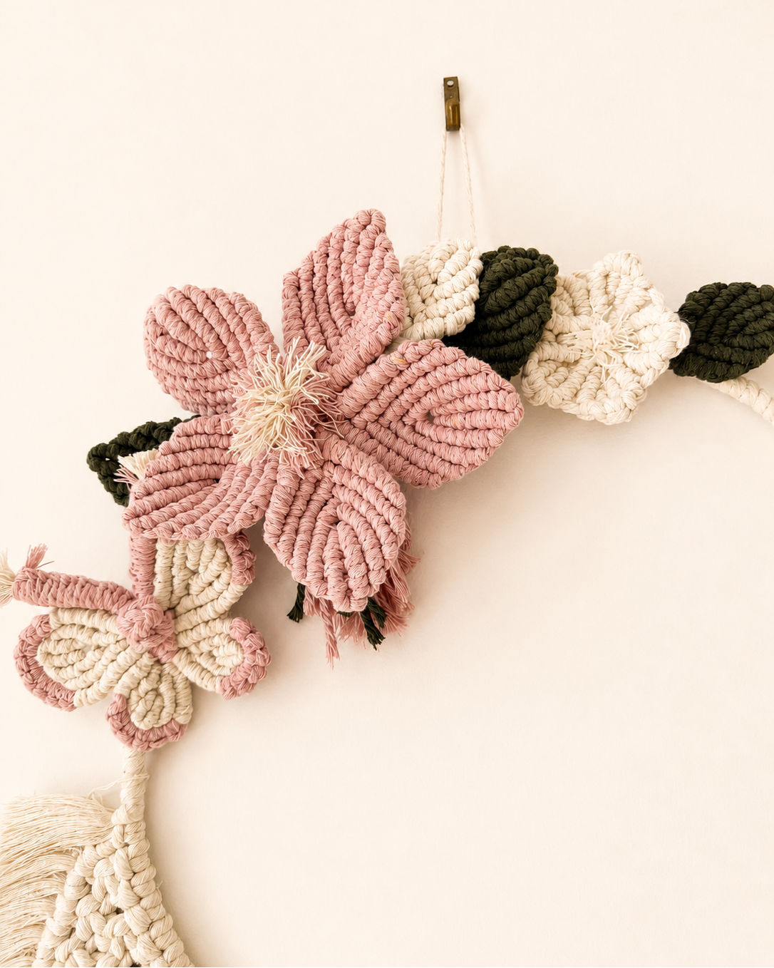 Handmade pink macrame flower and green leaves on floral wall hanging