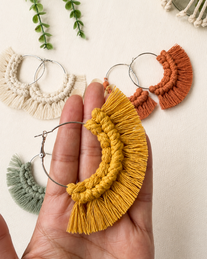 Close-up of handmade macrame fringe hoop earrings held in hand to show size and detail.