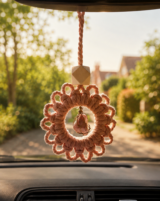 Handmade macrame gemstone car charm and essential oil diffuser hanging from a rear-view mirror inside a car.