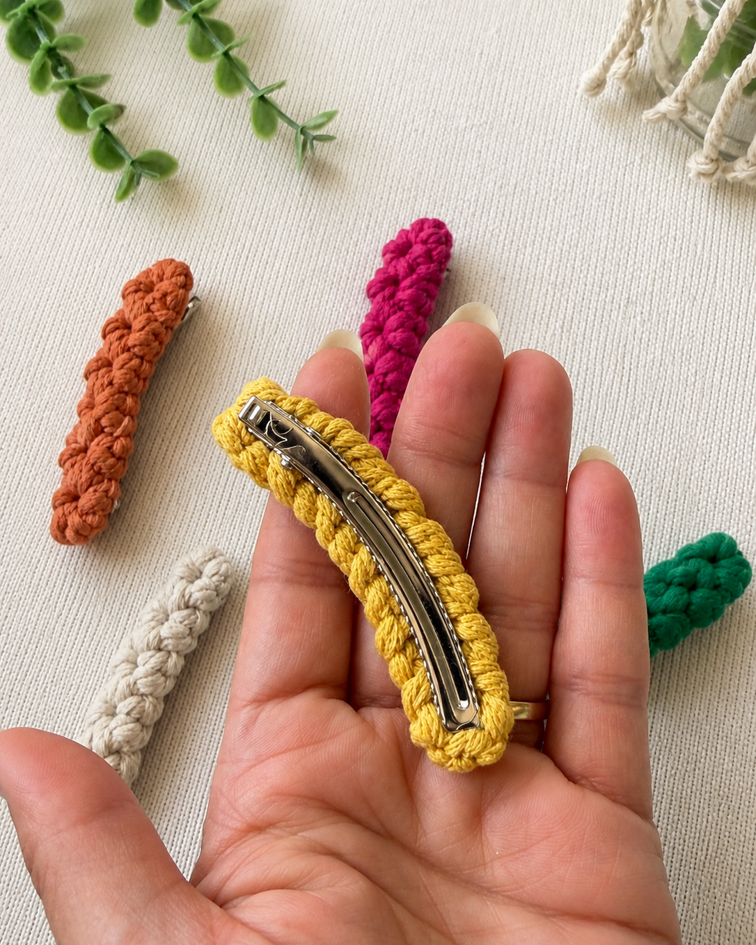 Back of handmade macrame hair clip showing the metal barrette while held in hand.