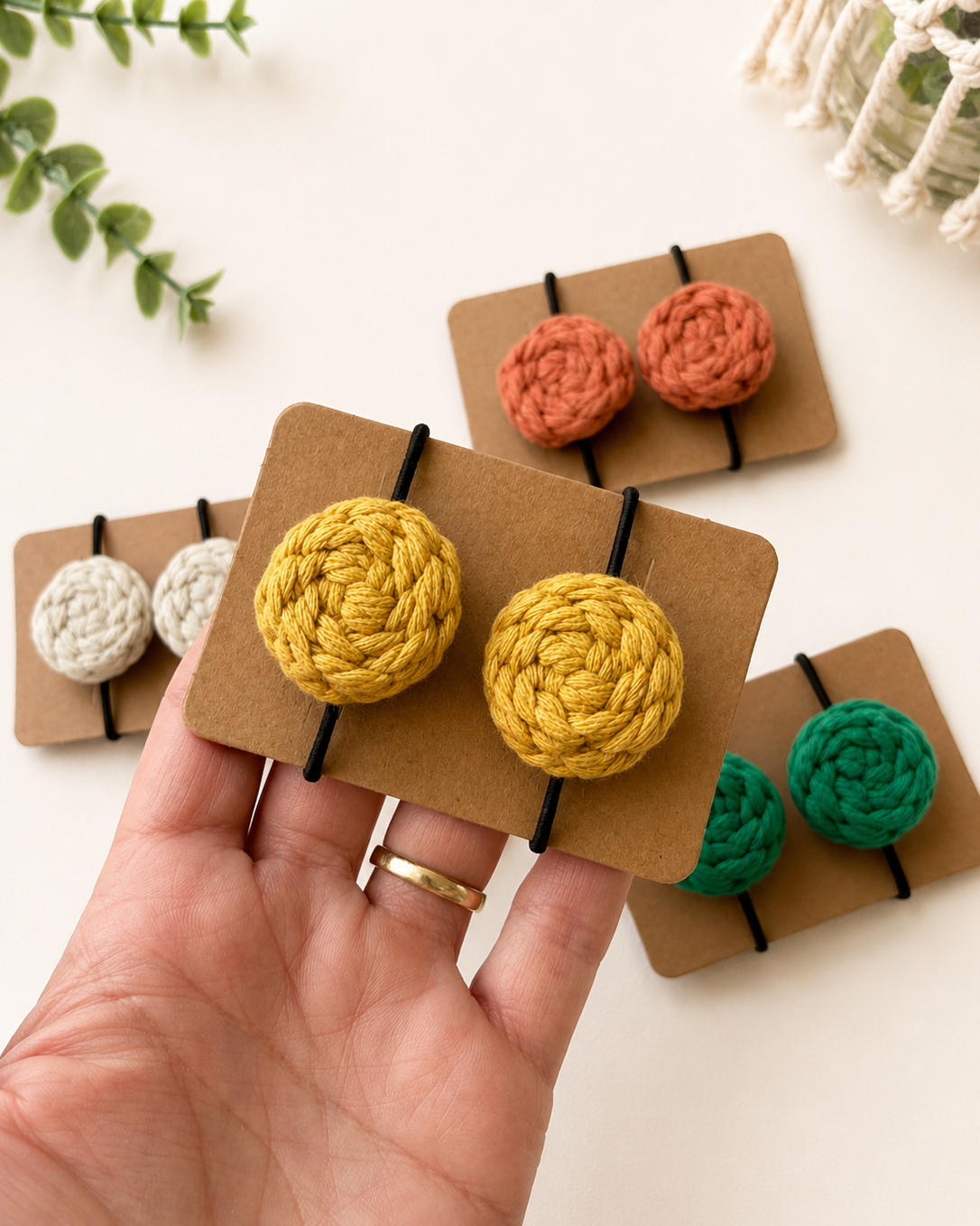 Hand holding handmade macrame cotton hair ties showing their size.