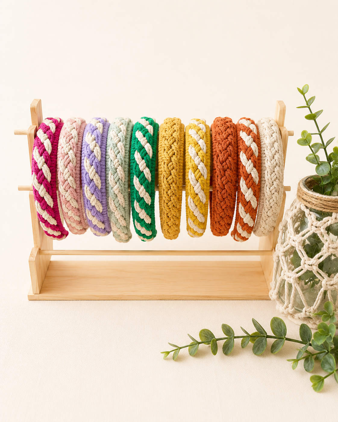 Handmade macrame headbands collection in multiple colours displayed on a wooden stand