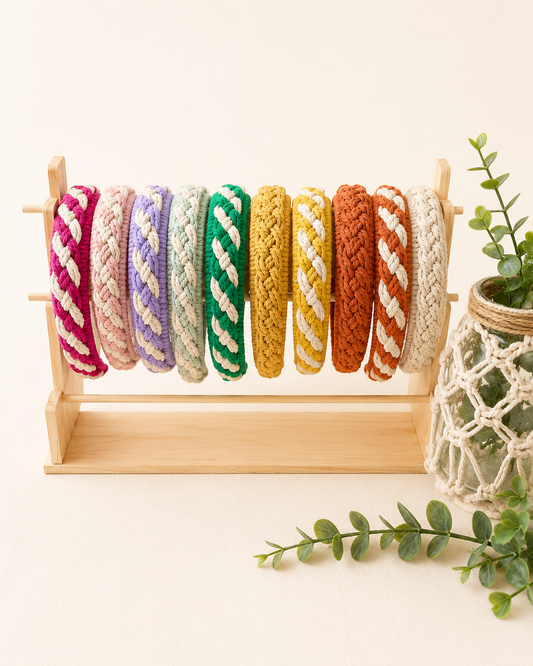 Handmade macrame headbands collection in multiple colours displayed on a wooden stand