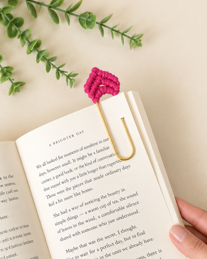Pink macrame heart bookmark clipped onto the page of an open book