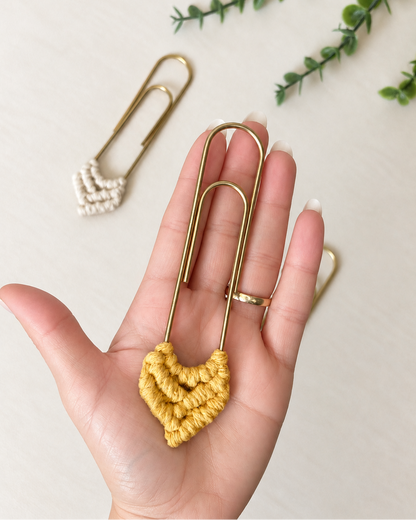Mustard macrame heart bookmark held in hand to show its size