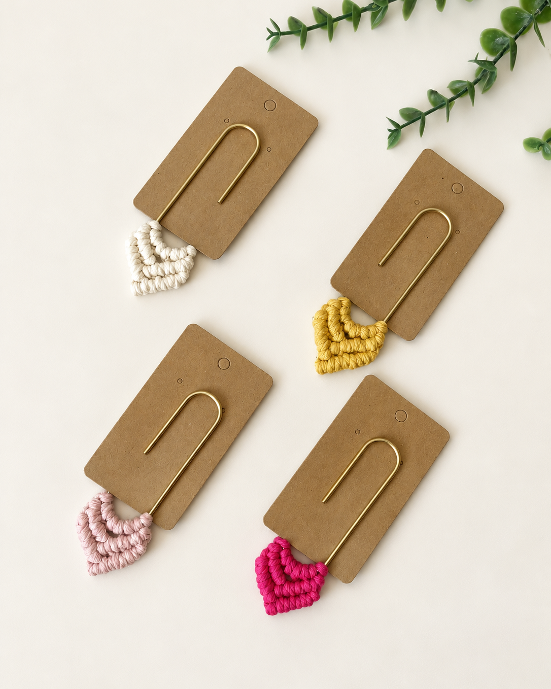 Four handmade macrame heart bookmarks displayed on kraft backing cards