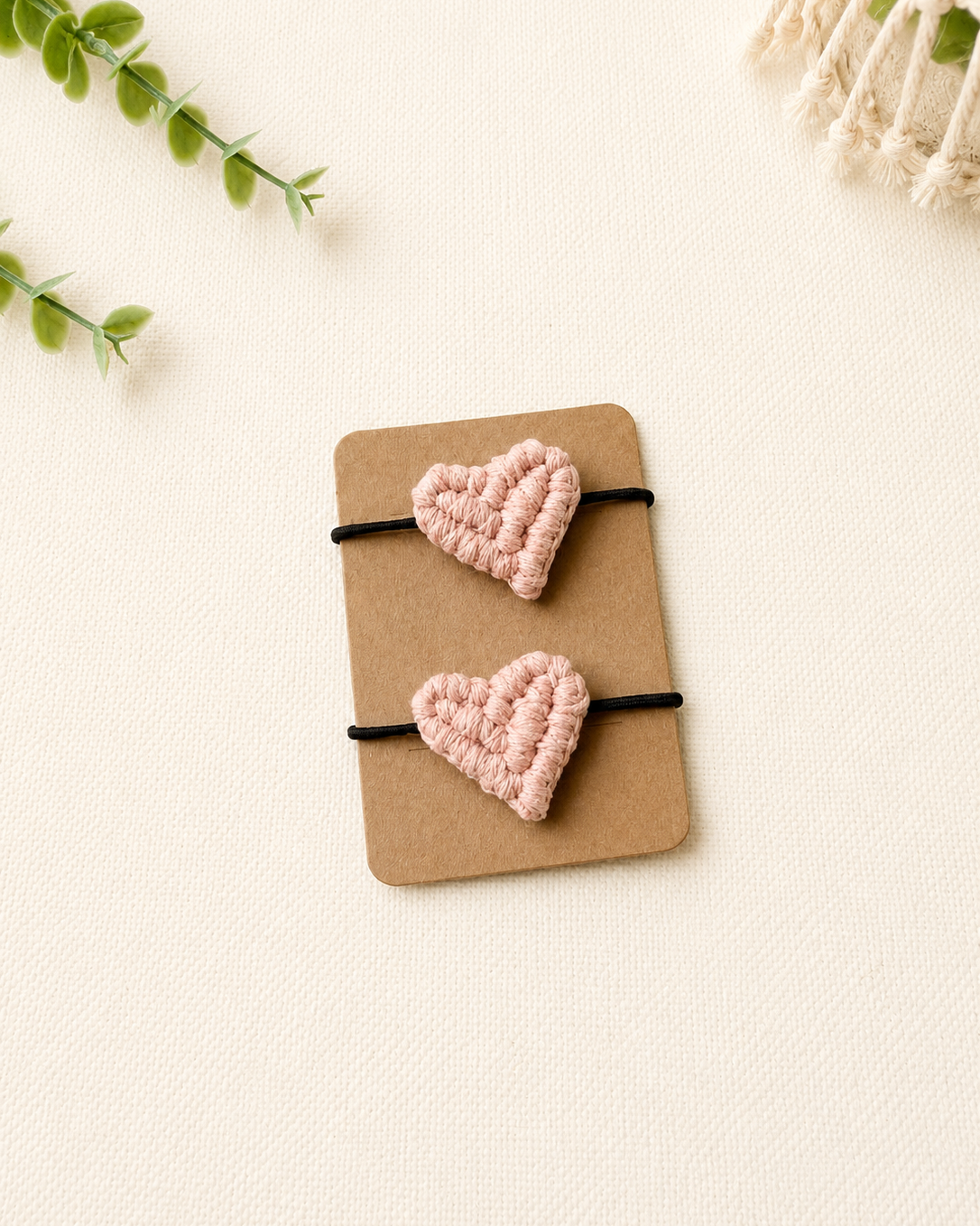 Handmade blush pink macrame heart hair ties on black elastic ponytail holders.