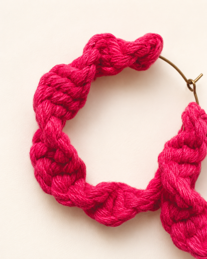 Close-up of handmade fuchsia macramé hoop earrings showing knot detail and texture
