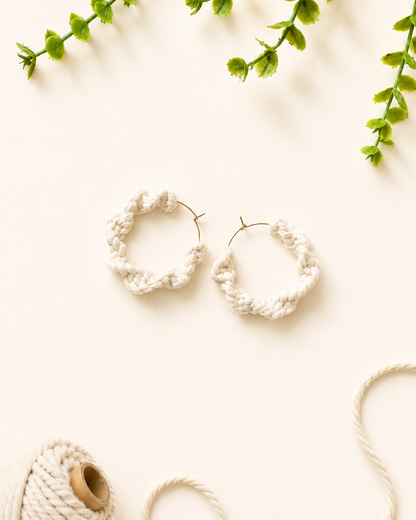 Off-white handmade macramé hoop earrings on a neutral fabric background
