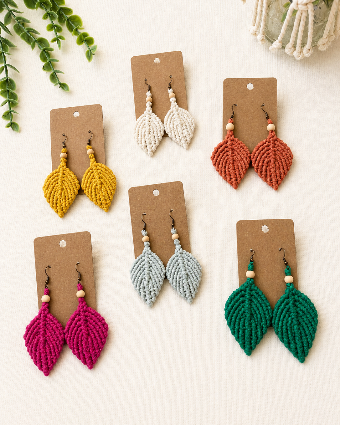 Handmade macrame leaf earrings displayed on kraft jewellery cards in six colours, ready for gifting.