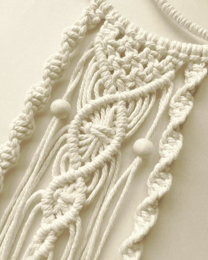 Close-up of the intricate knotwork and wooden bead details on a handmade macrame crescent moon wall hanging.