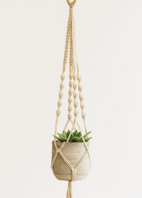 Off-white macramé plant hanger by Samra Knots, styled with a ceramic pot and succulent. Handmade boho decor using soft cotton cord.