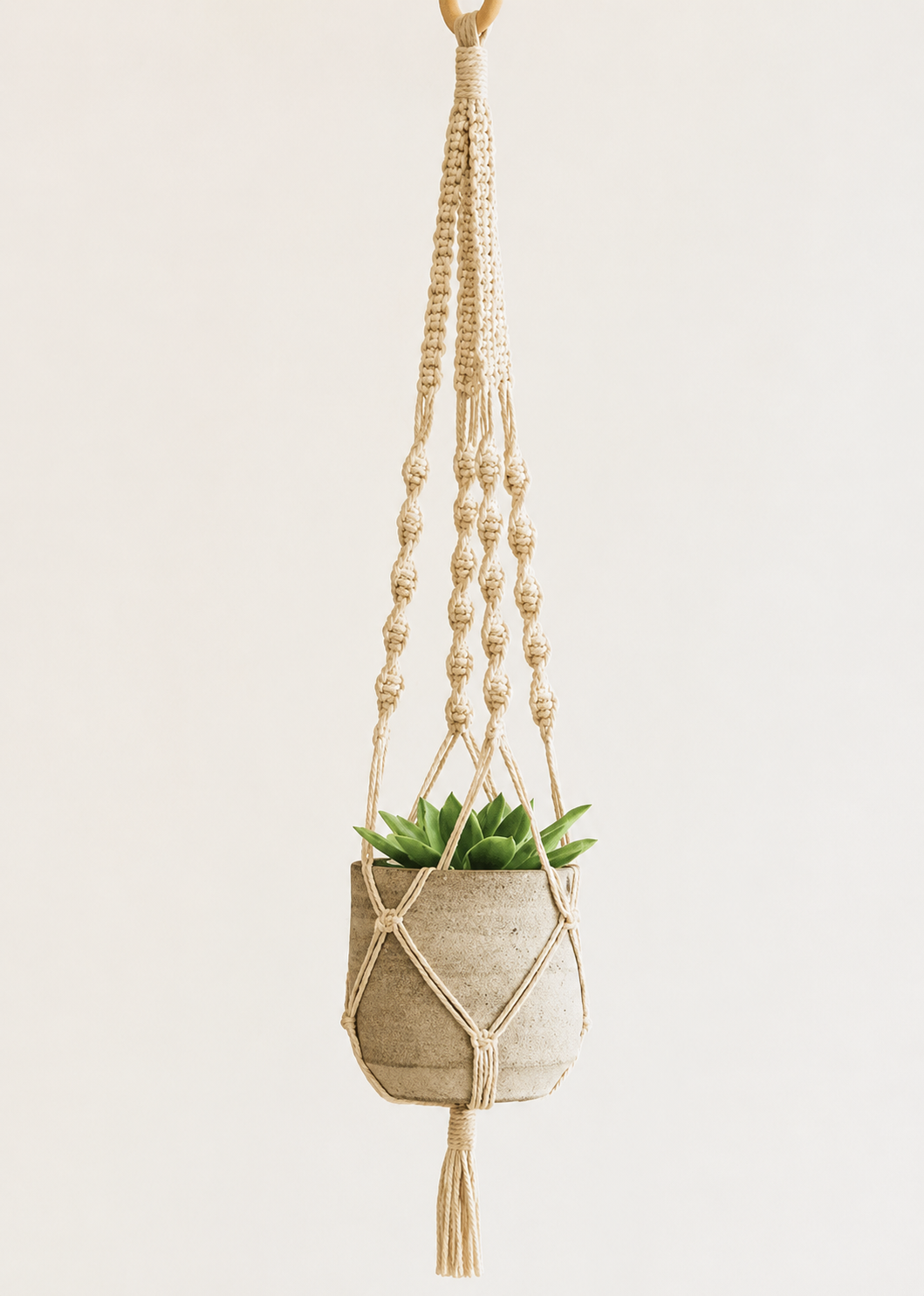 Off-white macramé plant hanger by Samra Knots, styled with a ceramic pot and succulent. Handmade boho decor using soft cotton cord.