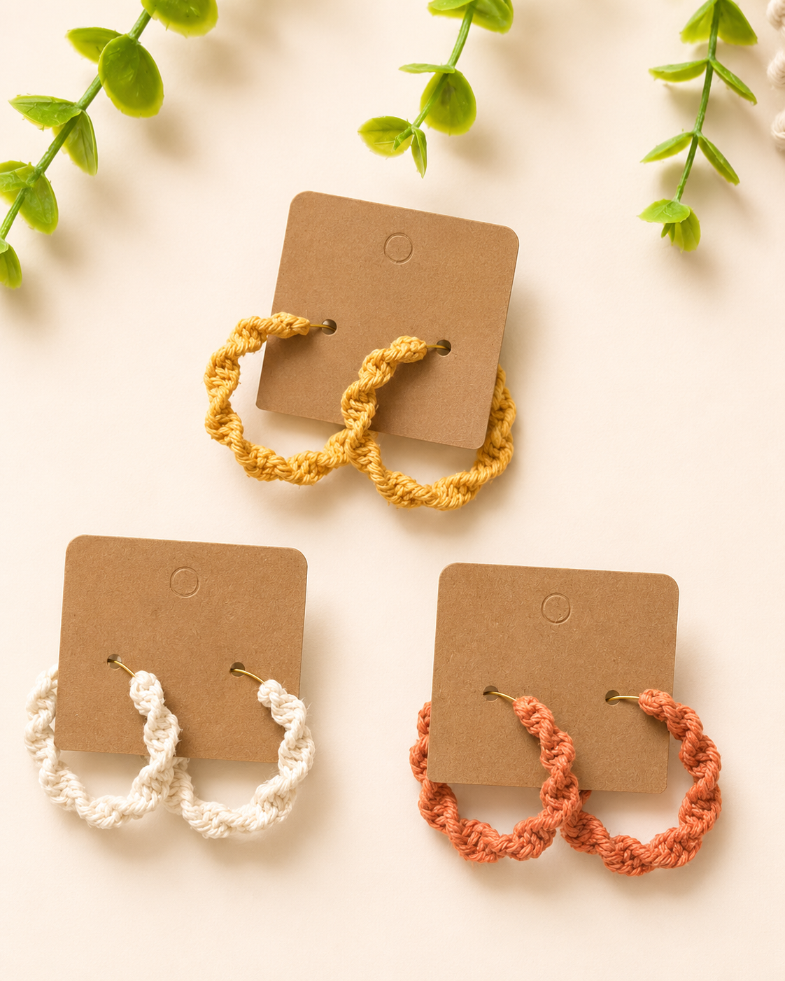 Macramé spiral hoop earrings displayed on kraft jewellery cards in three colours.