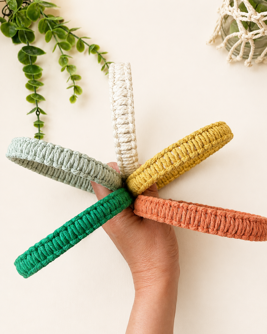 Handmade macrame square knot headbands in off white, mustard, terracotta, mint green and emerald green displayed together.