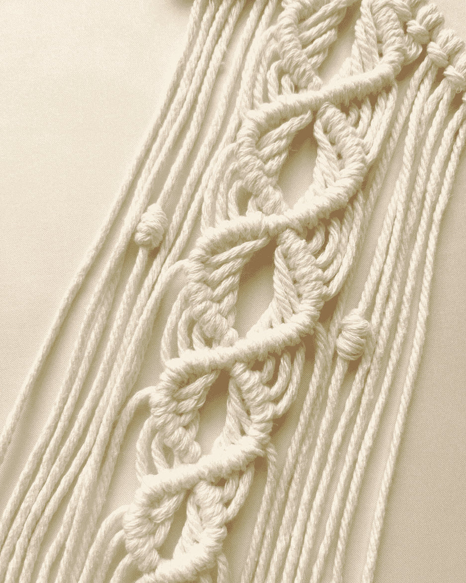 Close-up of handmade macrame star wall hanging showing intricate knot pattern and cotton fringe detail