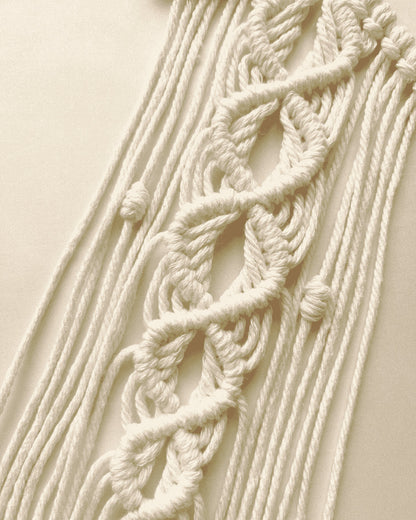 Close-up of handmade macrame star wall hanging showing intricate knot pattern and cotton fringe detail