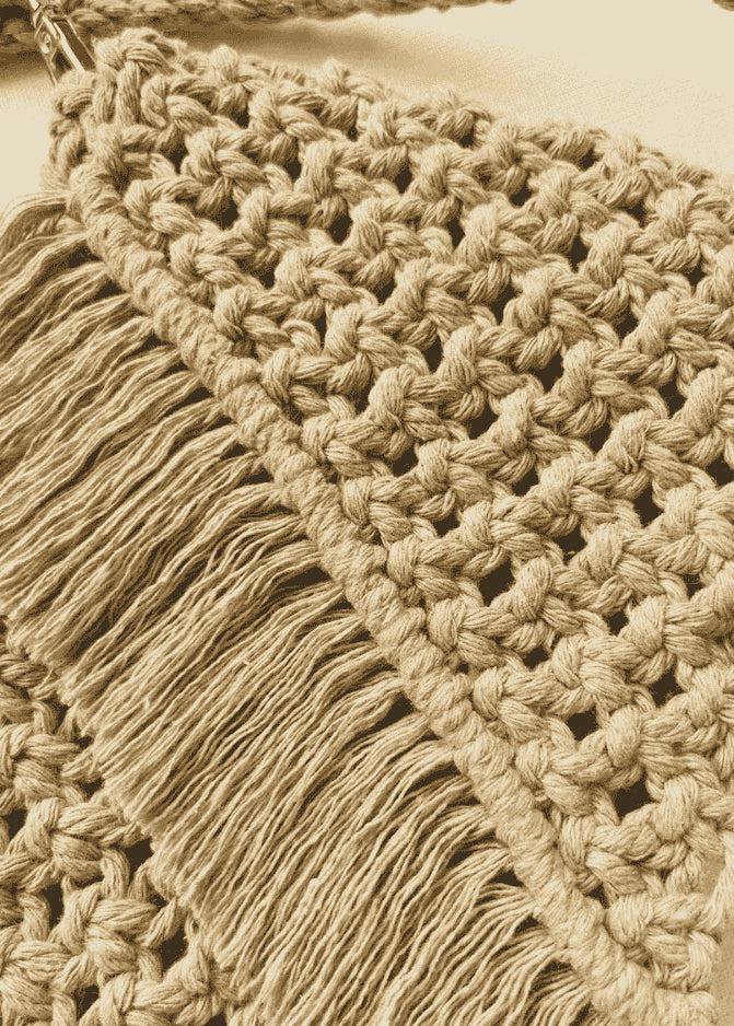 Light brown handmade macramé bag with diagonal fringe and detailed knot pattern, shown flat on an off-white fabric background.