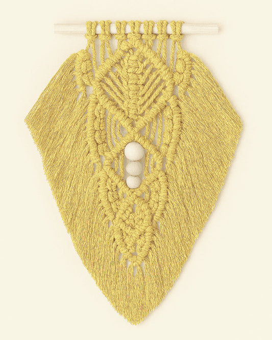 Bright mustard yellow macramé wall hanging with layered leaf pattern and natural wood beads, hanging on light neutral surface.