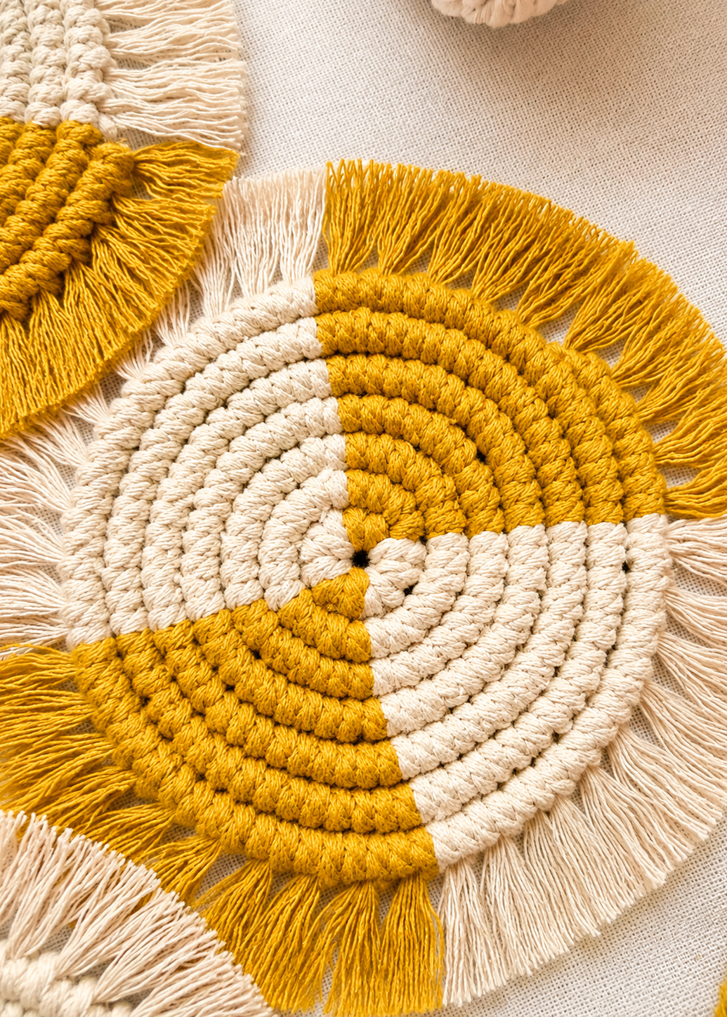 Close-up of a yellow and beige macrame wall hanging with fringes.