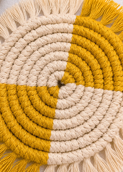 Close-up of a round woven mat with concentric circles in beige, mustard, and white.