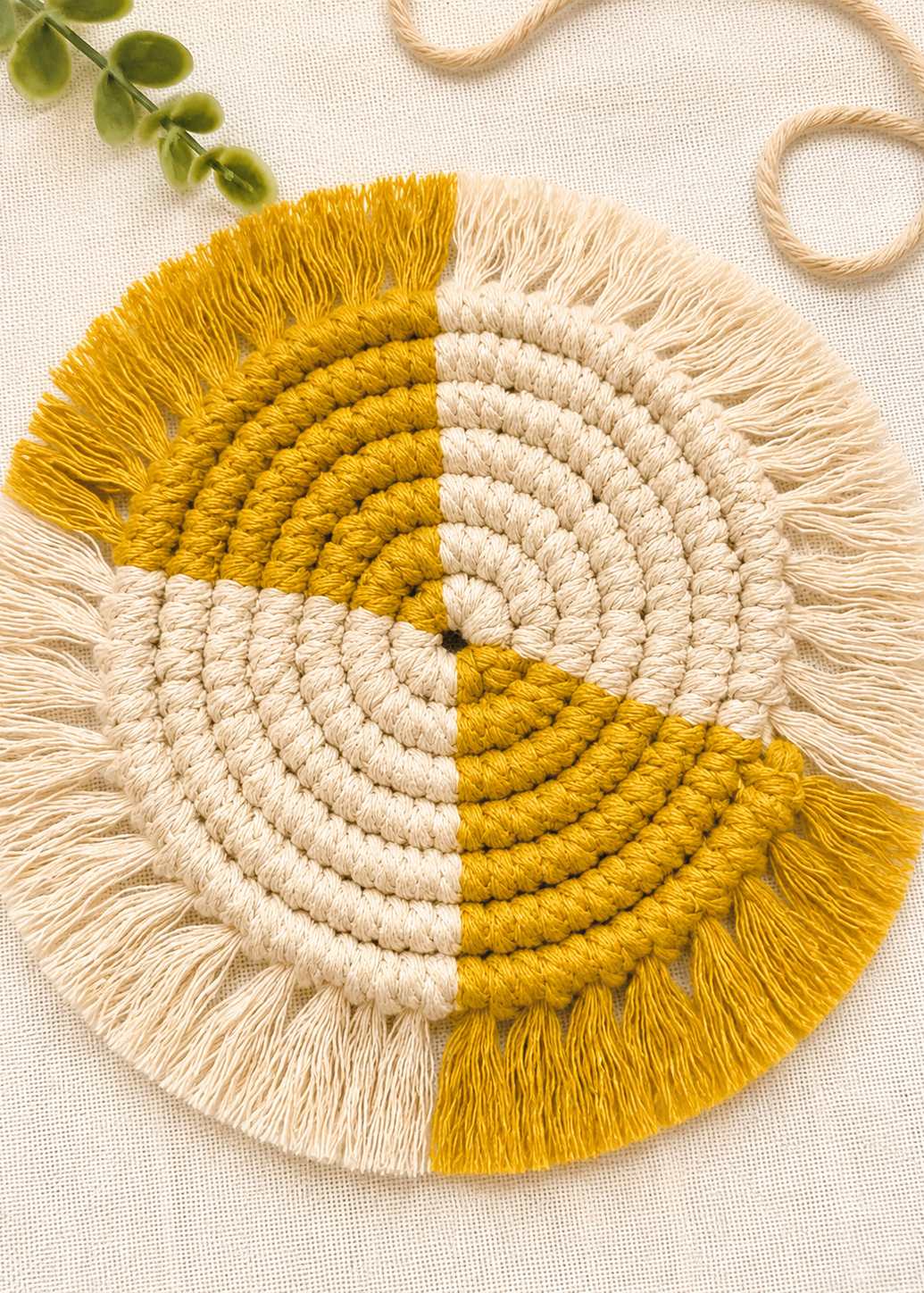 Round macrame wall hanging with yellow and beige colors on a light background