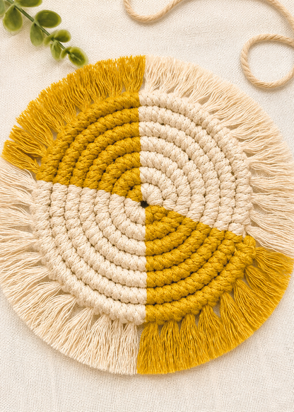 Round macrame wall hanging with yellow and beige colors on a light background
