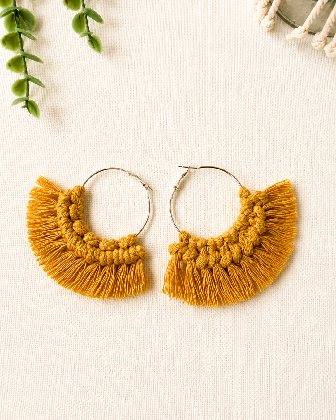 Close-up of handmade mustard macrame fringe hoop earrings showing knot details and fringe.