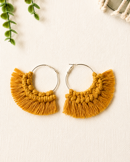 Close-up of handmade mustard macrame fringe hoop earrings showing knot details and fringe.