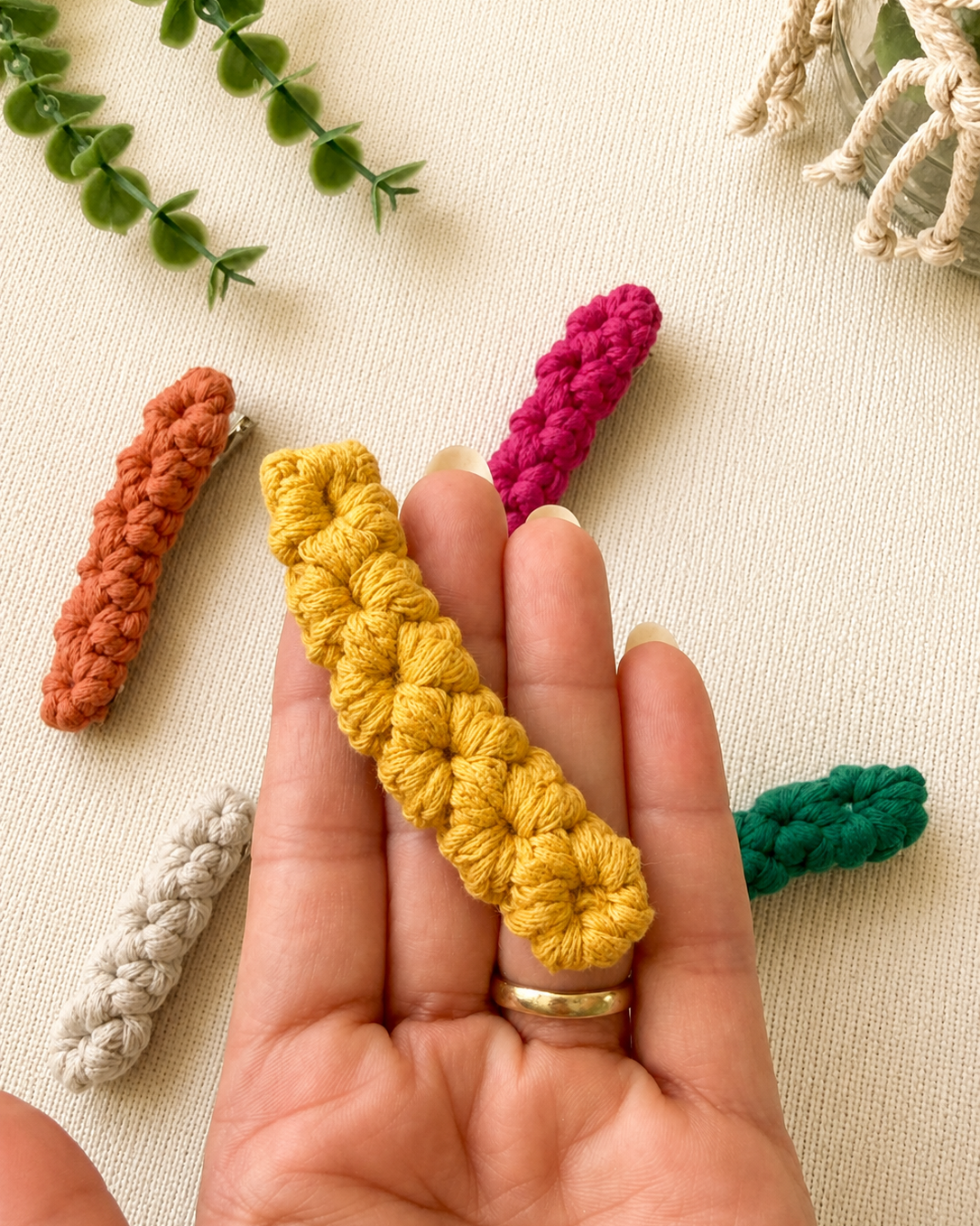 Close-up of handmade mustard macrame hair clip held in hand.