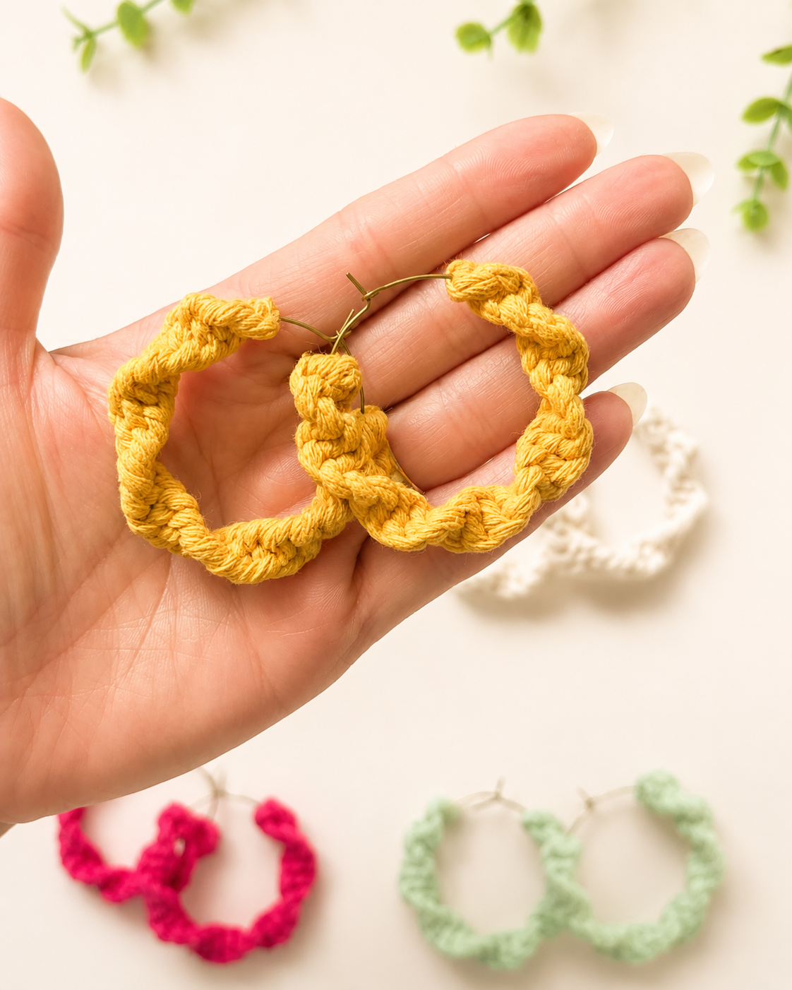 Hand holding mustard macramé hoop earrings showing size, texture and handmade detail