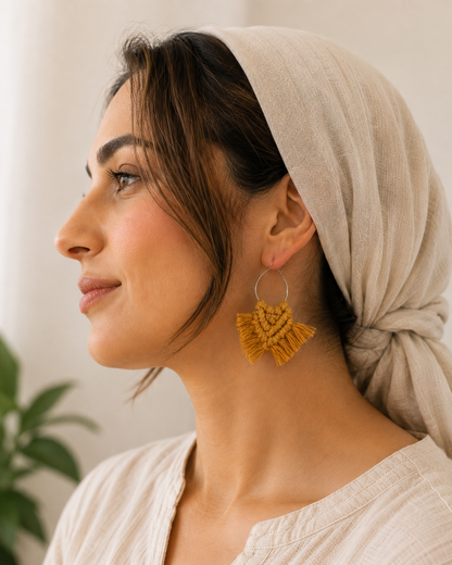 Woman wearing handmade mustard yellow macrame hoop earrings with silver hoops, lightweight boho statement earrings by Samra Knots.