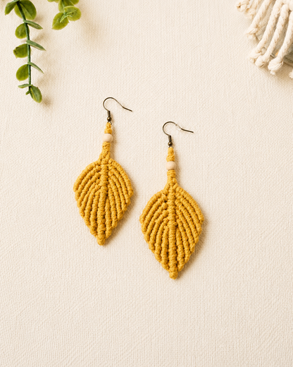 Handmade mustard yellow macrame leaf earrings with wooden bead detail and antique bronze hooks.